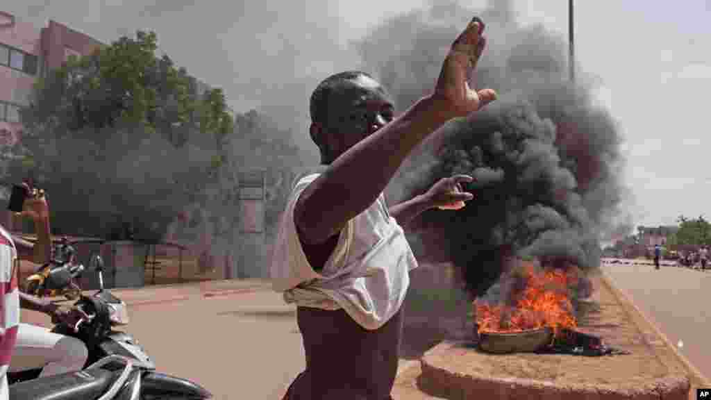 Un des manifestants lève sa main et vocifère devant des pneus enflammés à Ouagadougou, Burkina Faso, 17 septembre 2015.