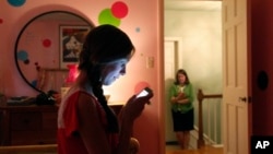 Teen girl, foreground, texts her mother as they pose for a photograph in LaGrange, Ill., May 24, 2012 (file photo).
