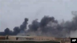 This image taken March 16, 2011 from amateur video and obtained March 17, 2011 shows a plume of smoke rising over the skyline in Ajdabiya, eastern Libya, the last major city between forces loyal to Libyan leader Moammar Gadhafi and rebel-held Benghazi