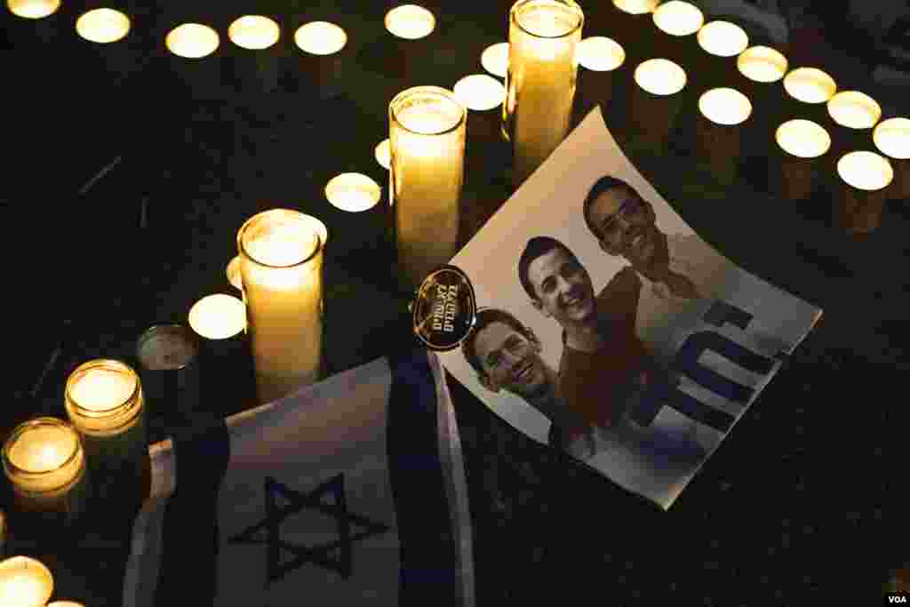 Candles are placed next to a picture of three Israeli teenagers who were abducted and killed, in Tel Aviv's Rabin Square, June 30, 2014.