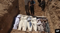 This image provided by Shaam News Network Aug. 22, 2013, which has been authenticated based on its contents and other AP reporting, purports to show several bodies being buried in a suburb of Damascus, Syria during a funeral on Aug. 21, 2013.