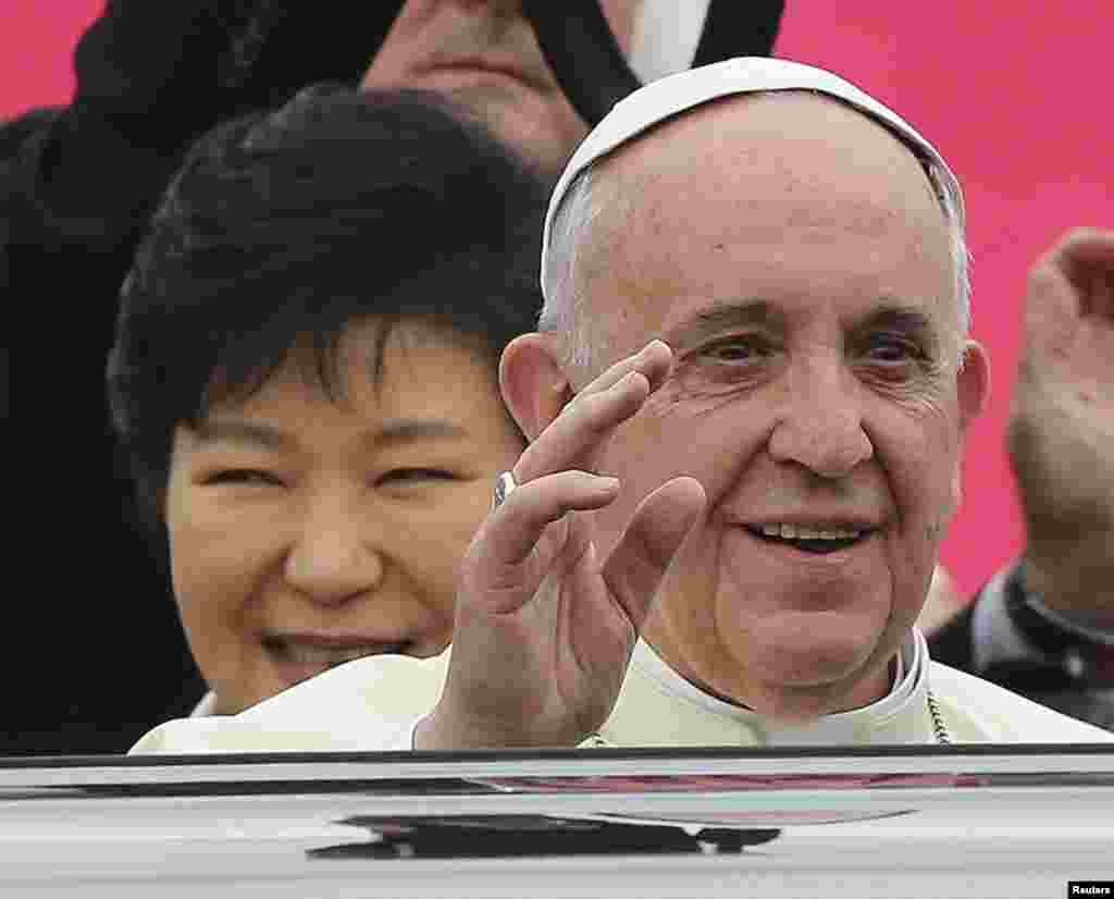 Pope Francis waves upon his arrival at Seoul Air Base, as South Korean President Park Geun-hye smiles, in Seongnam, Aug.14, 2014.