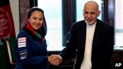 In this Monday, July 10, 2017 photo, Afghan President Ashraf Ghani shakes hands with Afghan-American female pilot Shaesta Waiz at the Presidential Palace in Kabul, Afghanistan.