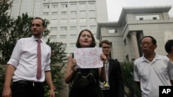 Li Wenzu, center, wife of imprisoned lawyer Wang Quanzhang, holds a paper that reads "Release Liu Ermin" as she and supporters of a prominent Chinese human rights lawyer and activists stage a protest outside the Tianjin No. 2 Intermediate People's Court in Tianjin, China on Aug. 1, 2016.