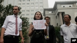 FILE - Li Wenzu, center, wife of imprisoned lawyer Wang Quanzhang, holds a paper that reads "Release Liu Ermin" as she and supporters of a prominent Chinese human rights lawyer and activists stage a protest outside the Tianjin No. 2 Intermediate People's Court in Tianjin, Aug. 1, 2016. 