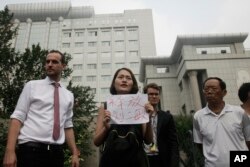 Li Wenzu, center, wife of imprisoned lawyer Wang Quanzhang, holds a paper that reads "Release Liu Ermin" as she and supporters of a prominent Chinese human rights lawyer and activists stage a protest outside the Tianjin No. 2 Intermediate People's Court i
