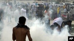 Anti-government protesters react to tear gas fired by riot police along a main highway in Manama, Bahrain, March 13, 2011