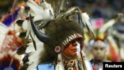 A dancer wearing a headdress of buffalo horns and a bird head watches the Denver March Pow Wow in Denver, Colorado, March 18, 2005. Buffalo provided Plains tribes with food, clothing, tools, shelter, and was central to tribes' spiritual beliefs.