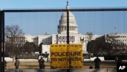 Penjaga nasional terlihat di pagar yang didirikan untuk memperkuat keamanan di sekitar Gedung Capitol, Washington. D.C., 13 Januari 2021 (Foto AP / Shafkat Anowar)