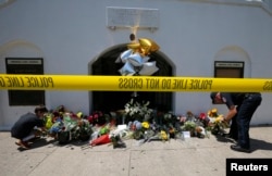 FILE - Liam Eller, 9, left, helps a police officer move flowers left behind outside Emanuel African Methodist Episcopal Church when the street was reopened a day after a mass shooting in Charleston, South Carolina, June 18, 2015. Dylann Roof was convicted of murder and hate crime charges in the attack in December 2016.