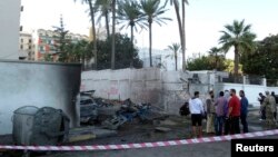 Onlookers and security personnel stand at the scene of a car bomb explosion near the Egyptian embassy in the Libyan capital of Tripoli Nov. 13, 2014. (Reuters)