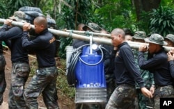 Soldiers carry a pump to help drain the rising floodwater in a cave where 12 boys and their soccer coach have been trapped since June 23, in Mae Sai, Chiang Rai province, in northern Thailand, July 6, 2018.