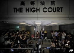 Newly elected Hong Kong lawmakers Yau Wai-ching (centre left) and Sixtus Leung talk to journalists during a press conference outside the high court in Hong Kong, Nov. 15, 2016. A Hong Kong High Court judge ruled that Sixtus Leung and Yau of the Youngspiration party violated a section of the semiautonomous Chinese city's constitution, the Basic Law, as well as laws covering oaths taken by officials.