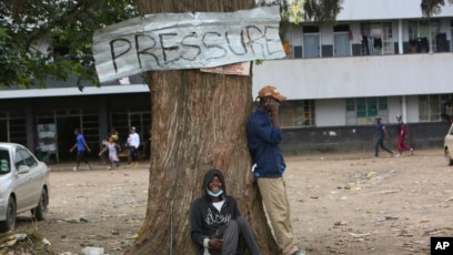 Two men relax under a tree in a poor township on the outskirts of the capital Harare, Nov, 16, 2021.