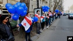 FILE - Supporters of the main opposition party wear Georgian national flags during a protest against buying gas from Russia's state-controlled Gazprom, in Tbilisi, Georgia, March 6, 2016. 