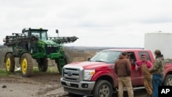 FILE - In this April 4, 2017, photo, Blake Hurst, a corn and soybean farmer and president of the Missouri Farm Bureau, second right, talks with his son Dallas Hurst, right, and his brothers Brooks Hurst, left, and Kevin Hurst, second left, on his farm in