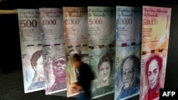 A man walks past banners showing banners depicting Venezuela's currency, the Bolivar, at the Central Bank of Venezuela in Caracas on Jan. 31, 2018.