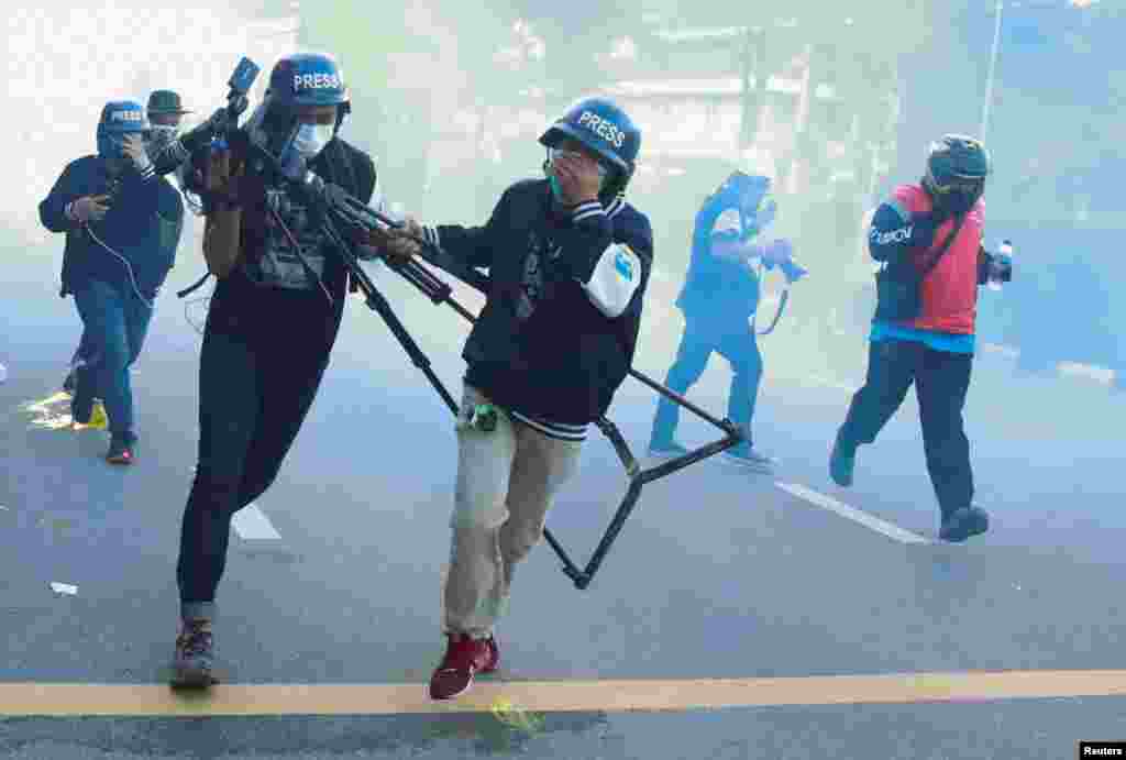 Members of the media run as they react to tear gas during a protest over the government&#39;s handling of the COVID-19 pandemic, in Bangkok, Thailand.