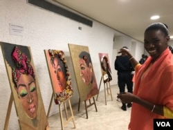 Tatou Dembele, a painter and owner of a food marketing company, points to her favorite of her own paintings. (E. Sarai/VOA)