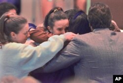 Members of the Columbine High School volleyball team hug the parents of Lauren Townsend, who was killed in the Colombine school shooting, after funeral services for Townsend in Littleton, Colorado, April 26, 1999.