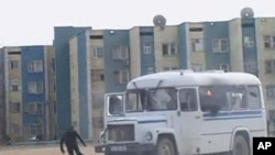A protester runs from a police vehicle in the Kazakh town of Zhanaozen in this still image taken from video acquired by Reuters TV, December 16, 2011.