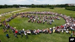 Protesters encircle a group standing to form letters that spell "Impeach Trump," during a rally to protest President Donald Trump and his policies, on the National Mall in Washington, June 3, 2017.