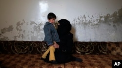 In this Jan. 18, 2017 photo, Elham Saleh, 31, who fled from the village of Deir Hafer, speaks with her son Abdullah, 4, as they sit in a room in the town of Safira, just south of Aleppo, Syria. 