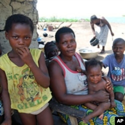An Ivorian mother sits in the shade with her children at the Koblakan river crossing in Liberia