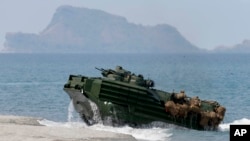 FILE – A U.S. Navy amphibious assault vehicle storms the beach in a joint exercise with American and Filipino troops at an island in the contested Scarborough Shoal, claimed by the Philippines and China, April 21, 2015. 