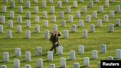 A member of the armed forces takes part in the Flags-In ceremony, where over 1,000 service members place flags in front of more than 260,000 headstones in Arlington National Cemetery in Arlington, Virginia, U.S., May 27, 2021. (REUTERS/Kevin Lamarque)