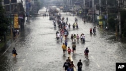 People walk on a flooded street in suburban Pasig City, east of Manila, Philippines, August 9, 2012.