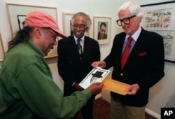 Artist and cartoonist Hank Ketcham (R) shows jazz pianist Horace Silver (L) his sketch of him as jazz composer Gerald Wilson looks on, in Los Angeles, April 17, 1999.