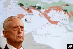 FILE - Secretary of Defense Jim Mattis stands in front of a map of Syria and Iraq, while speaking to the media at the Pentagon, May 19, 2017.