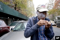 Luis Torres smokes a cigarette outside the New York City Housing Authority's Chelsea-Elliot Houses where he lives, Nov. 12, 2015, in New York.