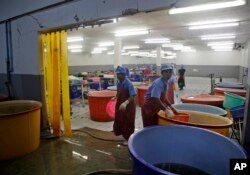 FILE - In this Monday, Nov. 9, 2015 file photo, workers react during a raid on a shrimp shed conducted by Thailand's Department of Special Investigation in Samut Sakhon, Thailand.