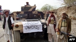 FILE - Armed militants of Tehrik-i-Taliban Pakistan (TTP) pose for photographs next to a captured armored vehicle in the Pakistan-Afghanistan border town of Landikotal, November 10, 2008.