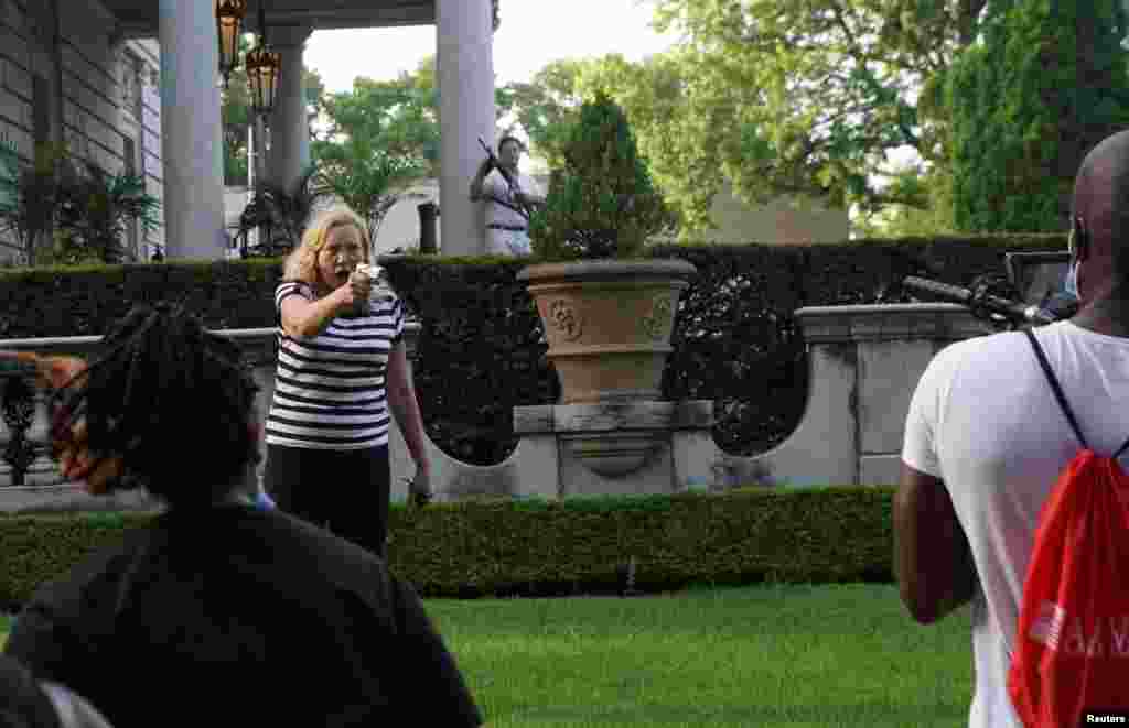 A couple holds their weapons toward protesters during a protest against St. Louis Mayor Lyda Krewson, in St. Louis, Missouri, June 28, 2020.