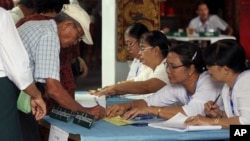 A voter signs his name to get a ballot sheet from an official of the Union Election Commission at a polling station in Yangon, Myanmar, April 1, 2017. Voting is underway in 19 by-elections in Myanmar, in the first test of the popularity of Aung San Suu Kyi’s National League for Democracy since it formed the government a year ago.