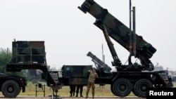 FILE - Dutch soldiers are seen standing next to a Patriot missile battery at a military base in Adana, southern Turkey, Jan. 26, 2013.