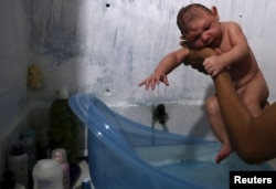 FILE - Daniele Santos, 29, holds her son Juan Pedro who is 2-months-old and born with microcephaly, after bathing him at their house in Recife, Brazil, Feb. 9, 2016.