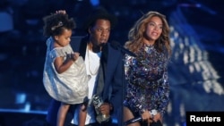 FILE - Jay-Z presents the Video Vanguard Award to his wife, Beyonce, as he holds their daughter, Blue Ivy, during the 2014 MTV Video Music Awards in Inglewood, California, Aug. 24, 2014.
