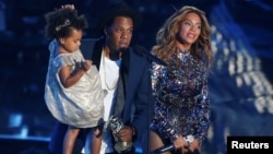 FILE - Jay-Z presents the Video Vanguard Award to his wife, Beyonce, as he holds their daughter, Blue Ivy, during the 2014 MTV Video Music Awards in Inglewood, California, Aug. 24, 2014.
