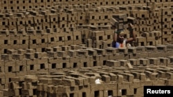 FILE - A laborer carries bricks at a kiln in Karjat, India, March 10, 2016. Thousands of brick kiln workers in India's western Maharashtra state are learning from activists that they have the right to a minimum wage, basic amenities and fair treatment.