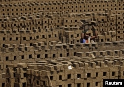 FILE - A laborer carries bricks at a kiln in Karjat, India, March 10, 2016. Thousands of brick kiln workers in India's western Maharashtra state are learning from activists that they have the right to a minimum wage, basic amenities and fair treatment.