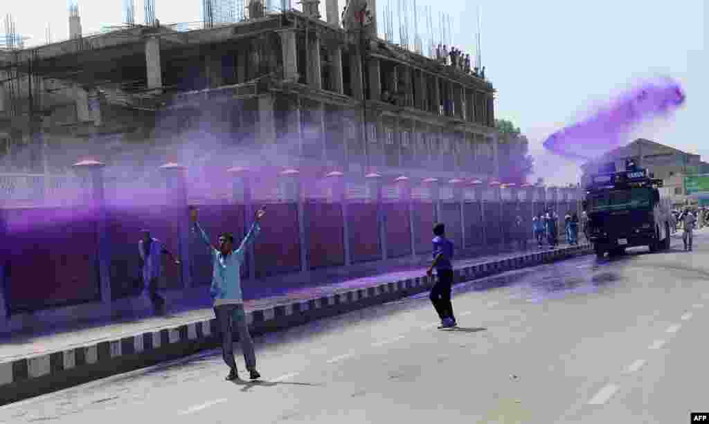 Kashmiri government employees are sprayed with a purple-dye water cannon by riot police during a demonstration in Srinagar, India. 