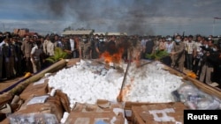 FILE: Police officers and people look on as government officials light a fire during a ceremony to dispose of confiscated drugs, in Phnom Penh August 28, 2012. 