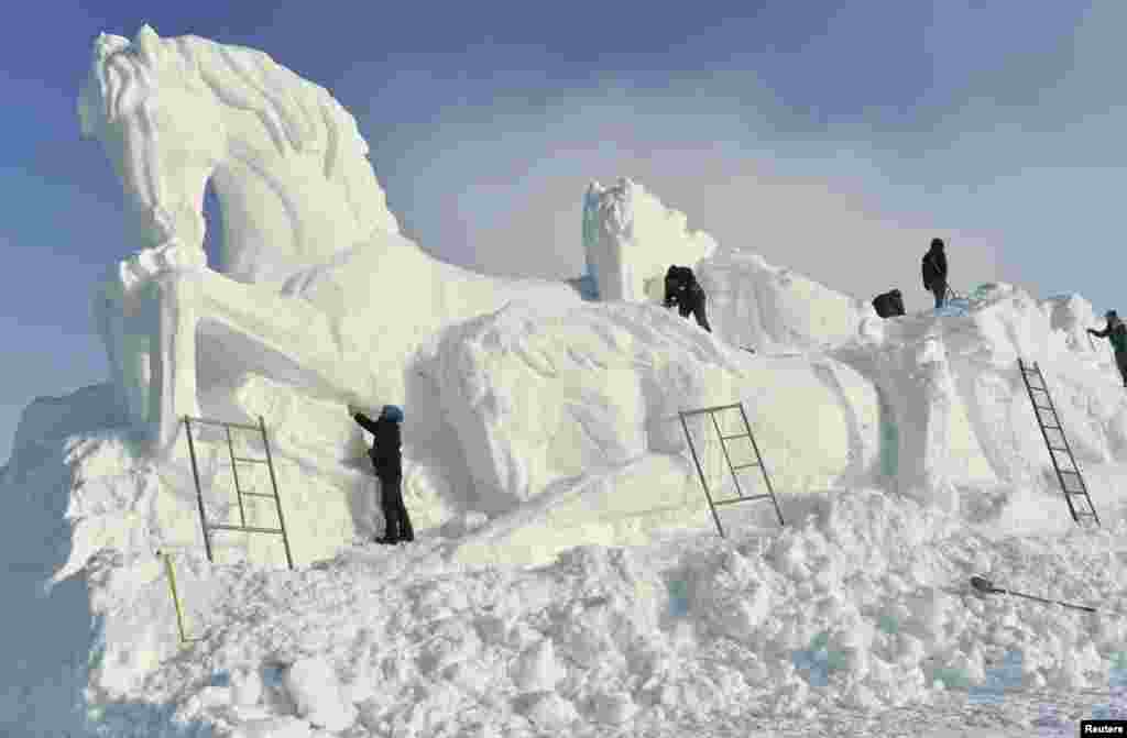 Workers shape a giant snow sculpture of horses ahead of an ice and snow festival in Barkol Kazakh Autonomous County, China&#39;s far western region of Xinjiang.