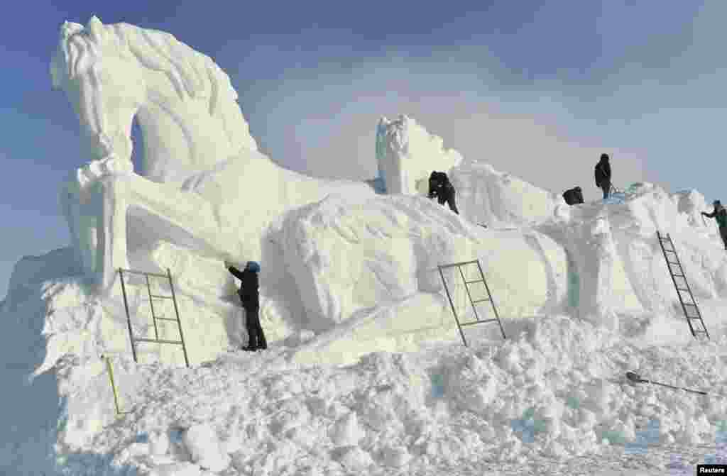 Workers shape a giant snow sculpture of horses, ahead of an ice and snow festival in Barkol Kazakh Autonomous County, China's far western region of Xinjiang.