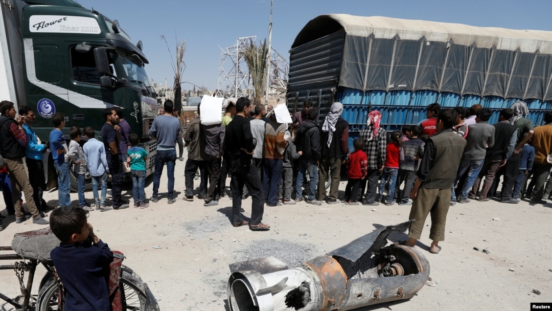 A boy stands next to the remains of a missile, in Douma, near Damascus, Syria, April 16, 2018.