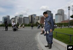 A man bows toward the Imperial Palace while listening to Emperor Akihito's message in Tokyo, Monday, Aug. 8, 2016.